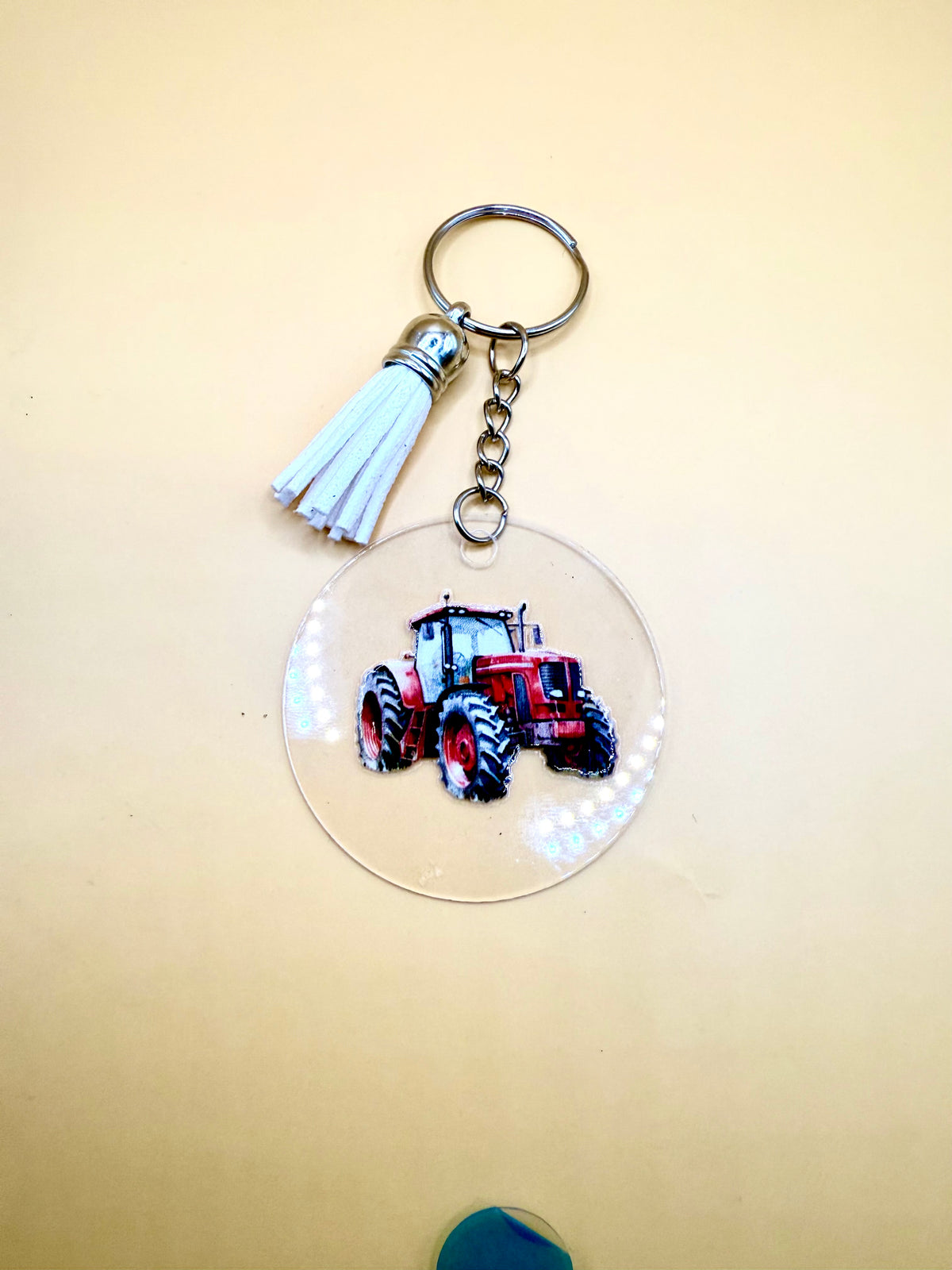Clear acrylic keyring charm printed with a red tractor, with a baby blue suede tassel and a silver split-ring keyring
